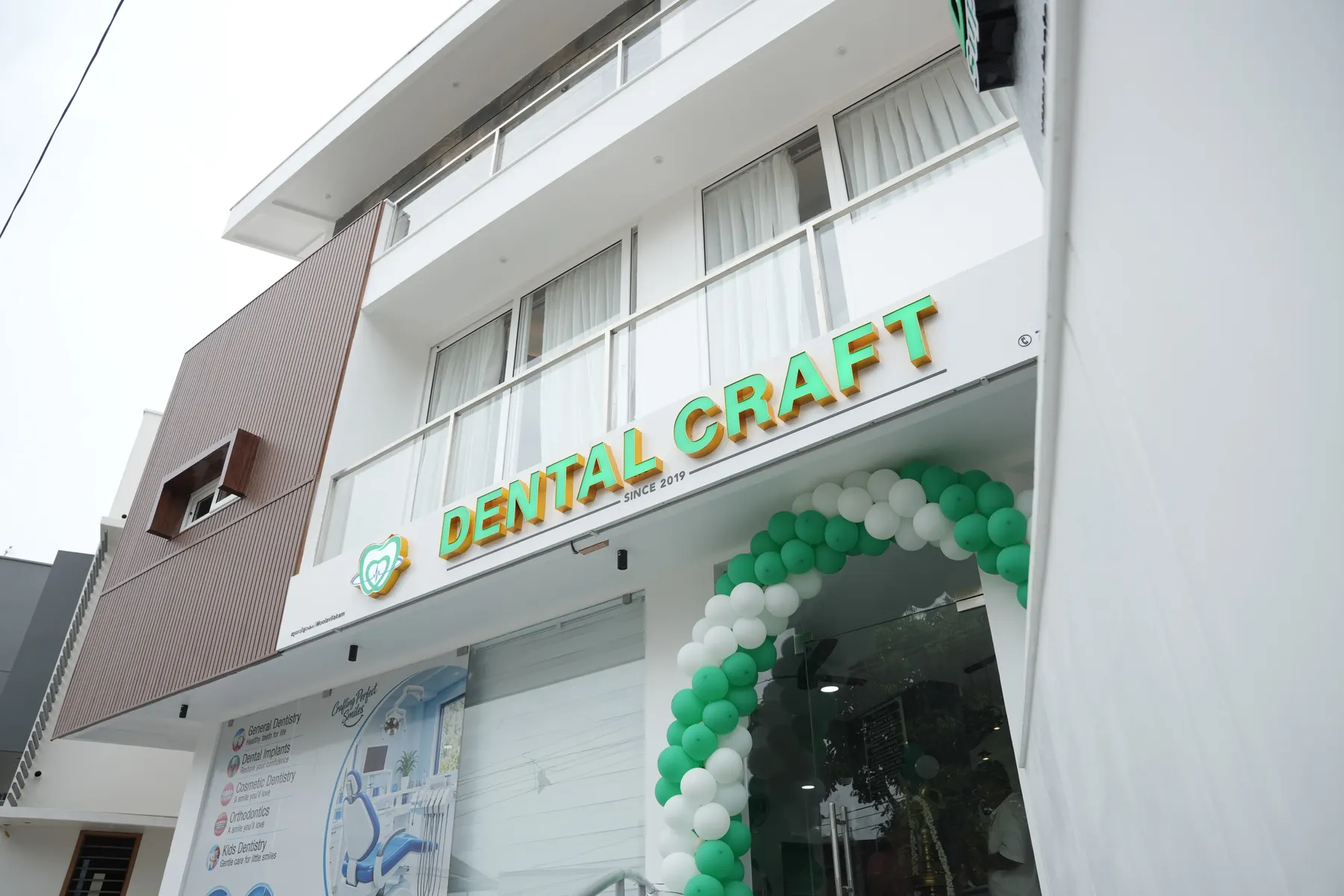 Entrance of Dental Craft Vanchiyoor decorated with a green and white balloon arch